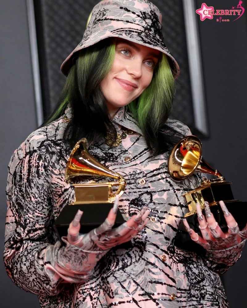 Billie Eilish accepts a music award on stage at an award ceremony.