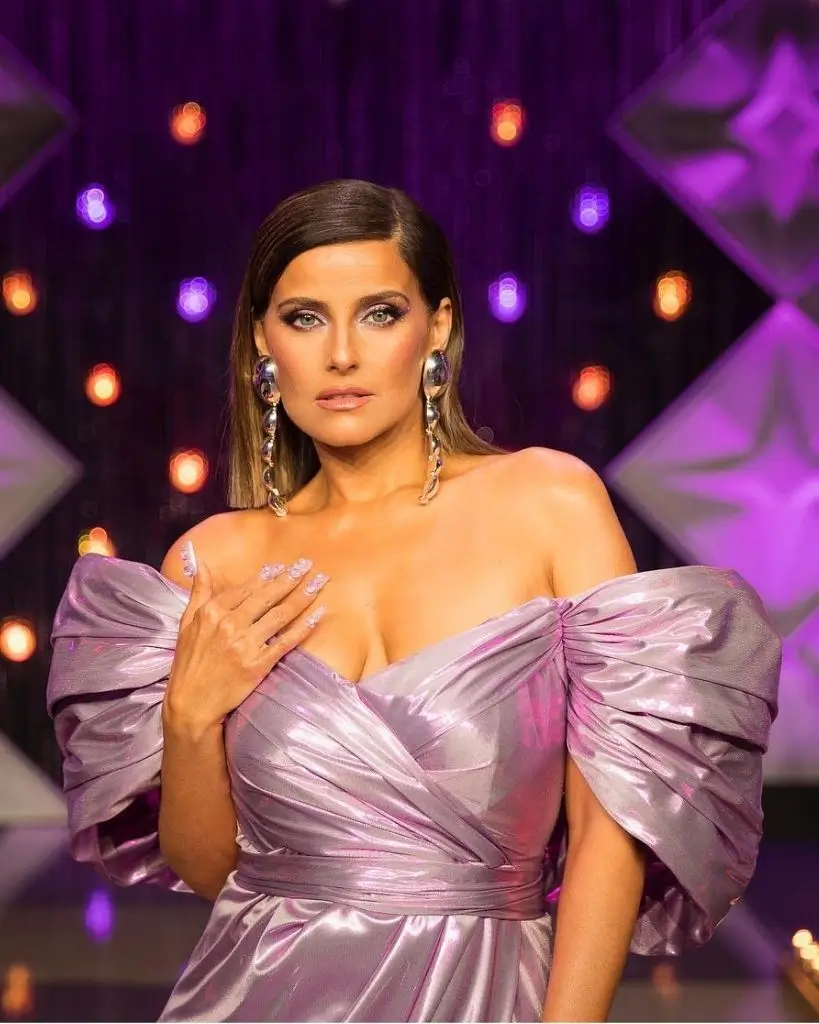 Nelly Furtado is possing on award show stage Nelly Furtado: A Canadian singer-songwriter known for her eclectic mix of pop, rock, and world music, Furtado rose to fame in the early 2000s with hits like 'I'm Like a Bird' and 'Turn Off the Light.' Her career is marked by her versatility, crossing genres and collaborating with artists globally.